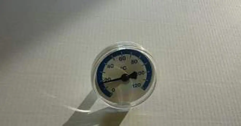 Thermometer von Remeha mit skaliertem Ziffernblatt zur Temperaturmessung, zeigt Werte von 0 bis 120 Grad Celsius an. Positioned auf einer hellen, strukturierten Oberfläche.